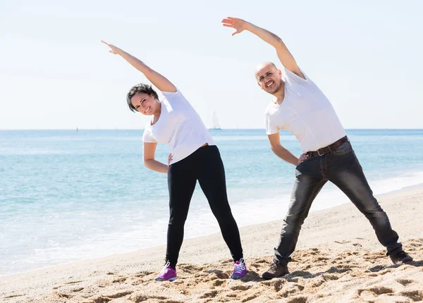 Homme et femme s'exerçant ensemble sur la plage — Photo