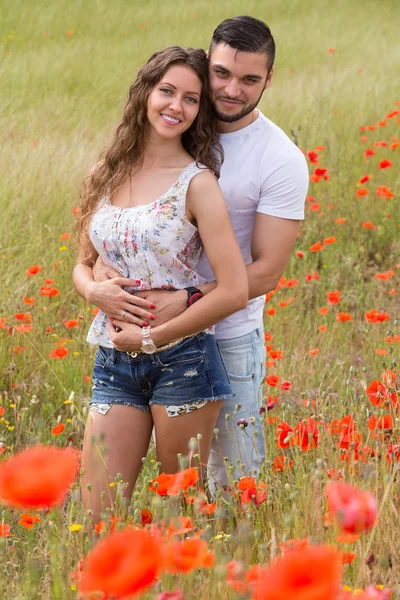 Casal sorridente em plantas de papoilas — Fotografia de Stock