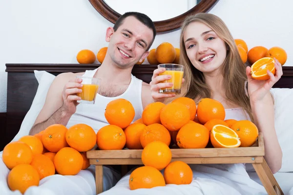 Couple with ripe oranges and freshly juice — Stock Photo, Image
