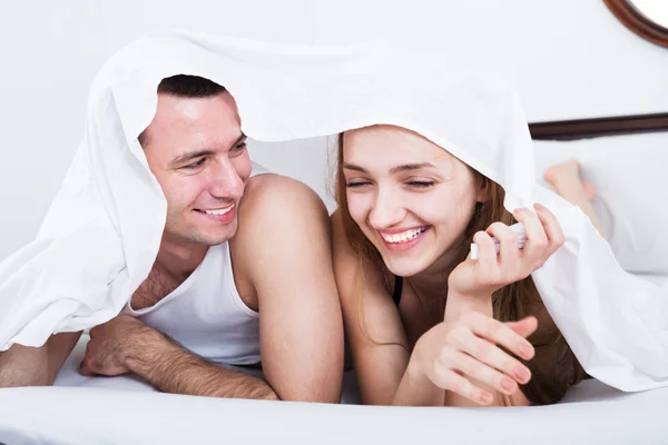 Loving couple hiding under cover — Stock Photo, Image