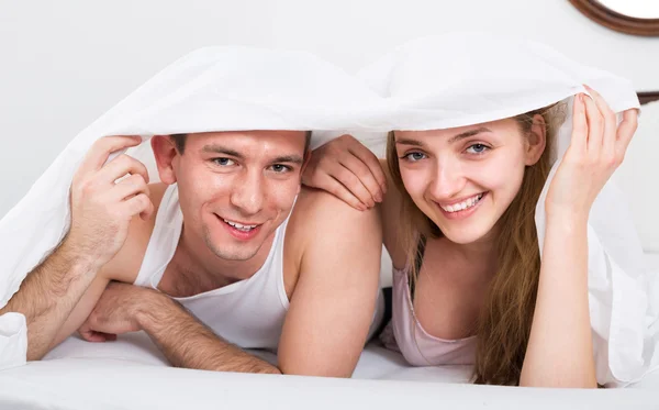 Couple in bed covered with sheet — Stock Photo, Image