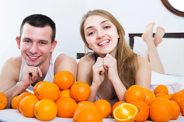 Pareja con naranjas en la cama Fotos de stock libres de derechos