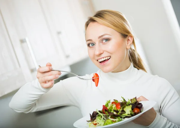 Veselý blond dívka jíst salát — Stock fotografie