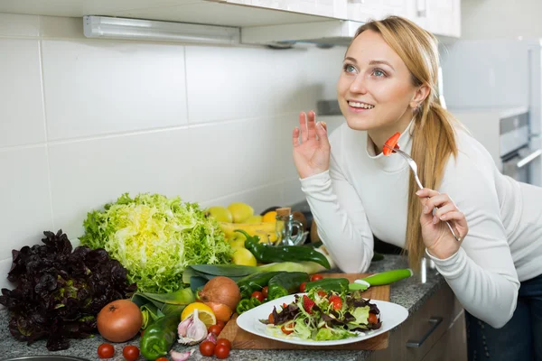 Vrolijk blond meisje eet salade — Stockfoto