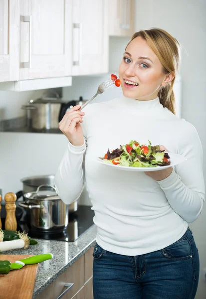 Vrolijk blond meisje eet salade — Stockfoto