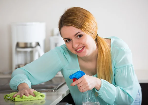 Νεαρή γυναίκα ξεσκόνισμα κουζίνα — Φωτογραφία Αρχείου