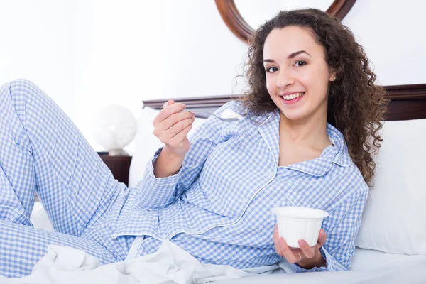 Donna con gustoso yogurt a letto — Foto Stock