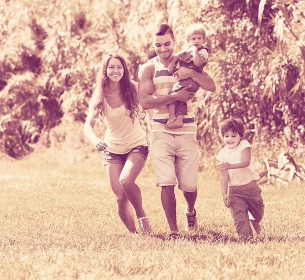 Familie van vier in zonnig park — Stockfoto