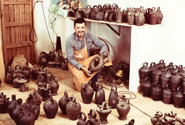 Potter sedí s keramickými nádobami — Stock fotografie