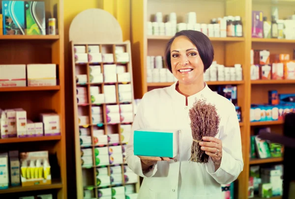 Donna con mazzo di erbe essiccate in farmacia — Foto Stock