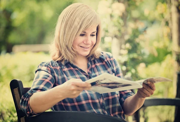 Mature woman with magazine in garden — Stock Photo, Image