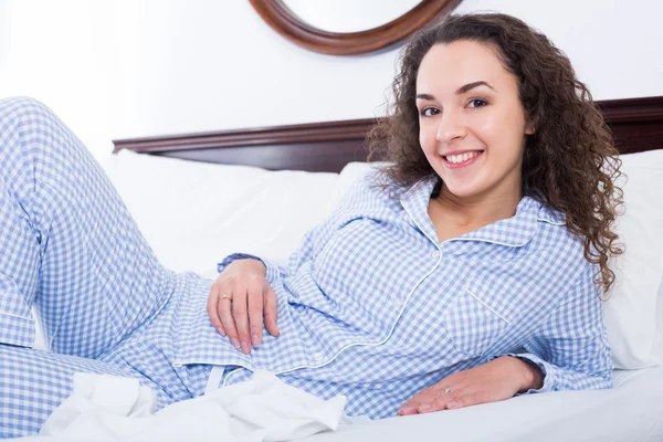 Femelle se prélassant au lit et souriant — Photo