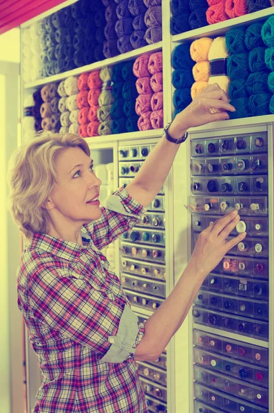 Mulher pegando carretéis de costura de algodão — Fotografia de Stock
