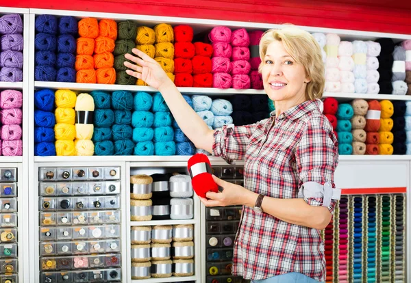 Cliente de pé ao lado da prateleira com fios de tricô — Fotografia de Stock