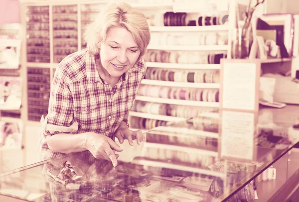 Mature woman near glass showcase in boutique — Stock Photo, Image