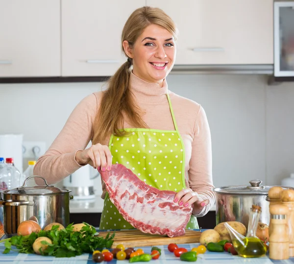 Happy blonde girl cooking ribs — Stock Photo, Image