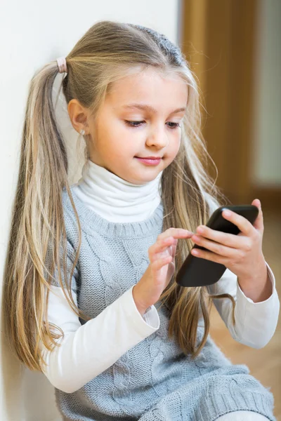 Meisje met mobiele telefoon binnen — Stockfoto