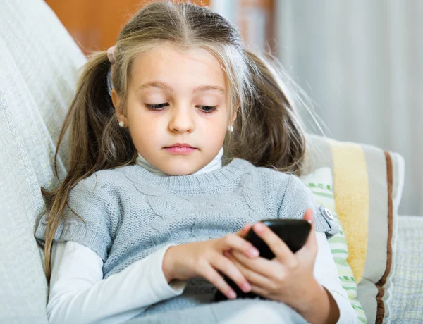 Meisje met mobiele telefoon binnen — Stockfoto