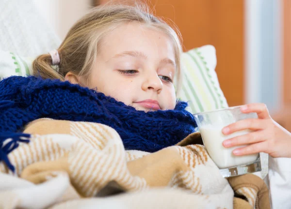 Girl under blanket with warm milk and fever — Stock Photo, Image