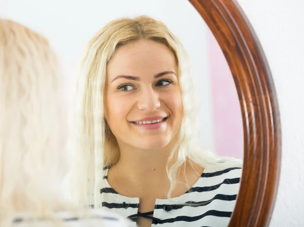 Meisje kijken naar zichzelf in de spiegel binnenshuis — Stockfoto