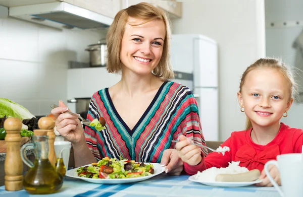Kvinna och liten flicka äter i köket — Stockfoto