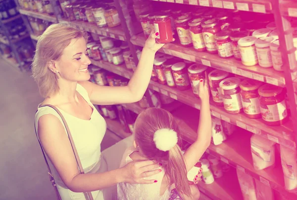 Woman with daughter choosing tomato sauce — Stock Photo, Image