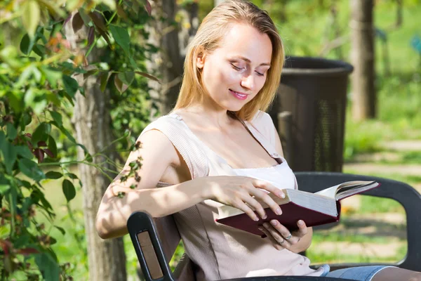 Mladá žena s knihou v zahradě — Stock fotografie
