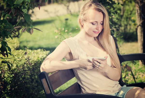 Young woman with smartphone in garden — Stock Photo, Image