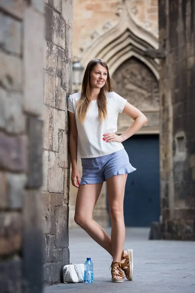 Junge Frau steht an alter Steinmauer — Stockfoto