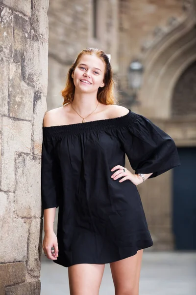 Hembra sonriente de pie cerca de la pared de piedra — Foto de Stock