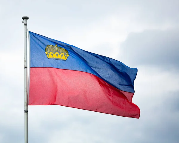 Bandera nacional de Liechtenstein en el fondo del cielo nublado — Foto de Stock