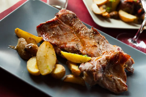 Lekker gekookt gebakken varkensvlees met gebakken aardappelen op bord — Stockfoto