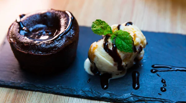 Dolce torta di lava servita con gelato alla vaniglia e menta al piatto nero — Foto Stock