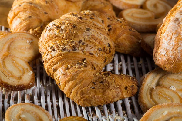 Croissant na macie rattanowej z innymi wyrobami piekarniczymi — Zdjęcie stockowe