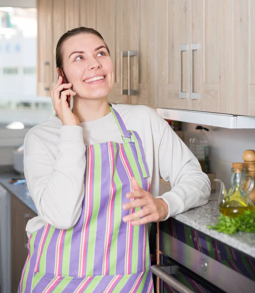Jeune femme parle par téléphone avec une petite amie dans la cuisine — Photo