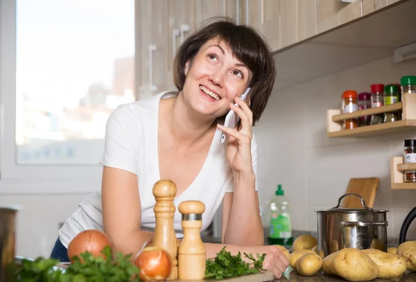 Kvinna pratar på sin smartphone i köket — Stockfoto