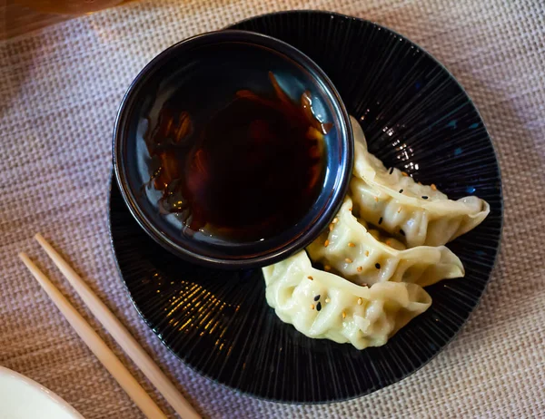 Gyoza - japonské knedlíky na černé misce se sójovou omáčkou — Stock fotografie