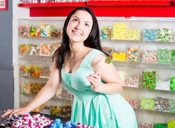 Усміхнена дівчина смокче lollypop в магазині — стокове фото