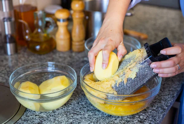 Rivning av potatis med hjälp av rivjärn för vegetabiliska pannkakor — Stockfoto