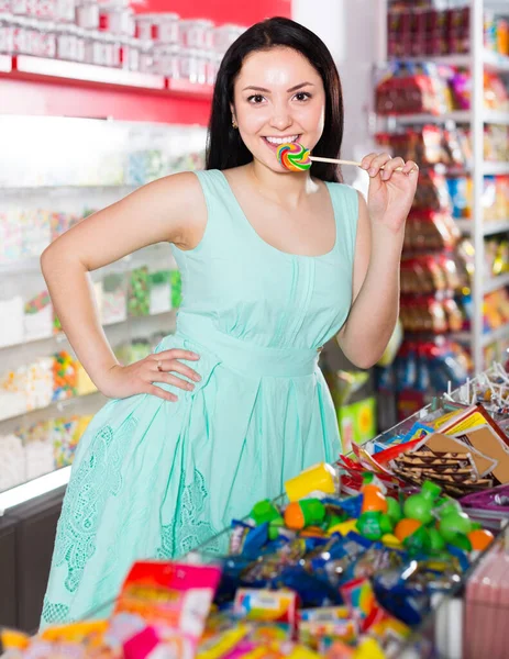 Sexy satisfecha mujer posando en la tienda con lolly —  Fotos de Stock