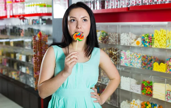 Sorridente ragazza succhiare lecca-lecca in negozio — Foto Stock