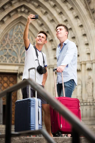 Dois homens com bagagem fazendo selfie durante excursão pela cidade em férias — Fotografia de Stock