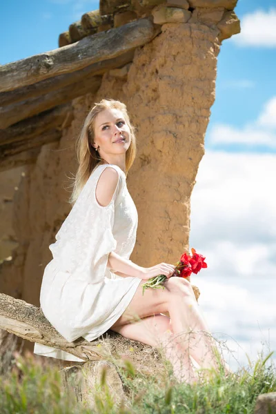 하얀 드레스를 입고 양귀비 꽃 과앉아 있는 아름다운 여인 — 스톡 사진