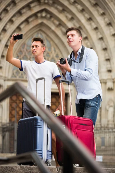 Manliga turister med bagage på gatan tar bilder — Stockfoto