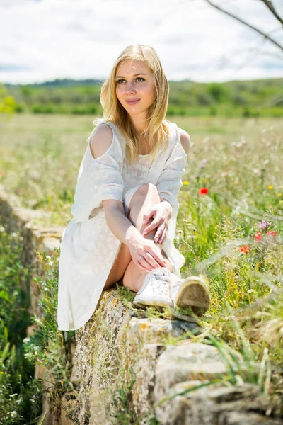 Portrait of beautiful young girl posing near field of wild flowers — Stock Photo, Image