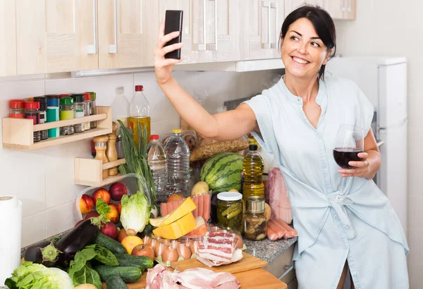 Kobieta robi selfie w pobliżu zakupów, które kupuje w sklepie spożywczym wewnątrz. — Zdjęcie stockowe