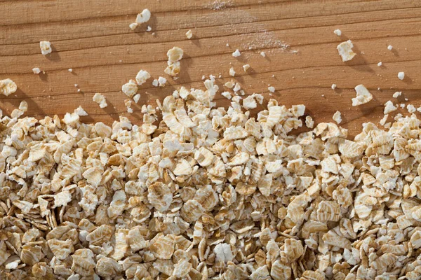 Oatmeal flakes on wooden surface — Stock Photo, Image