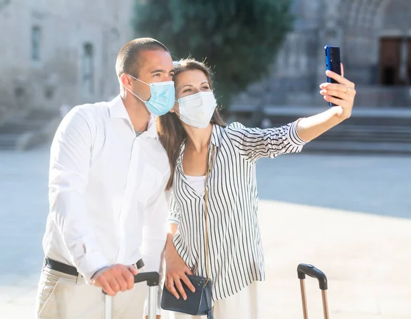 Felice coppia turistica in maschera prendendo selfie con il telefono — Foto Stock