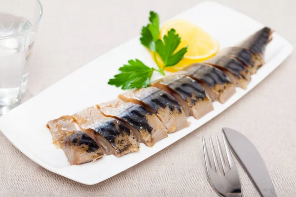 Smoked mackerel cut into pieces with parsley and lemon. — Stock Photo, Image