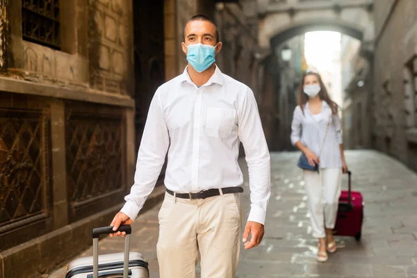 Homem na máscara facial andando com bagagem pela cidade — Fotografia de Stock